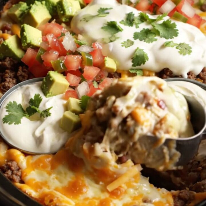 A warm, bubbling bowl of Texas Trash Dip served in a rustic stoneware crockpot with tortilla scoops.