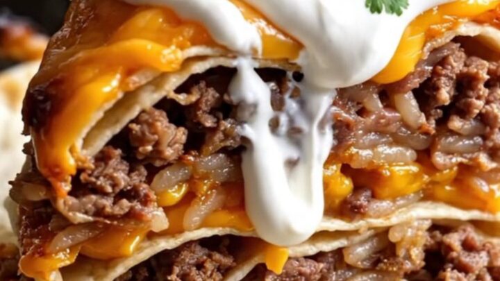 A close-up of a tall wedge of layered burrito bake showing beef, rice, beans, and melted cheese.