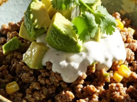 A warm, bubbling slow cooker filled with green chile beef and quinoa bake topped with melted cheese.