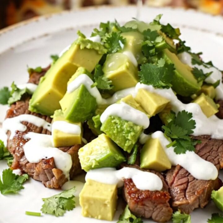A close-up of a slow cooker filled with tender steak strips, golden potatoes, and peppers covered in melted cheese.