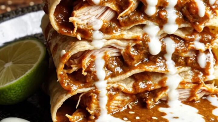 A tall, beautiful slice of chicken mole enchilada stack served on a plate with fresh garnishes.