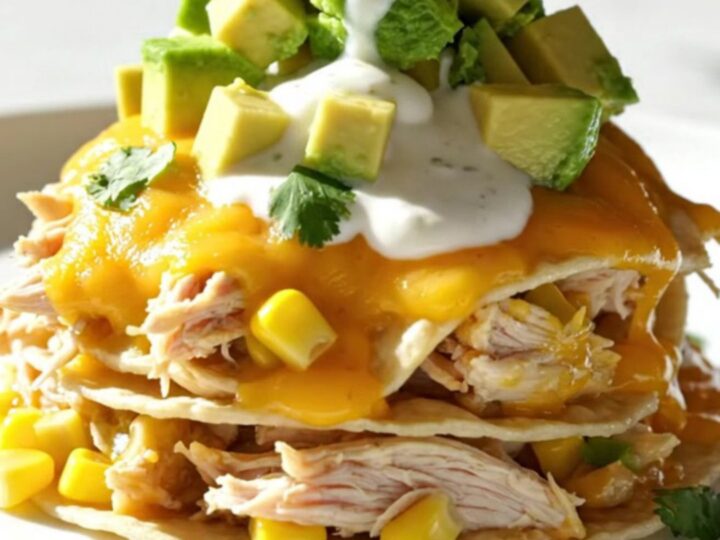 A close-up of the creamy cilantro lime chicken and white corn enchilada bake in a white ceramic slow cooker.