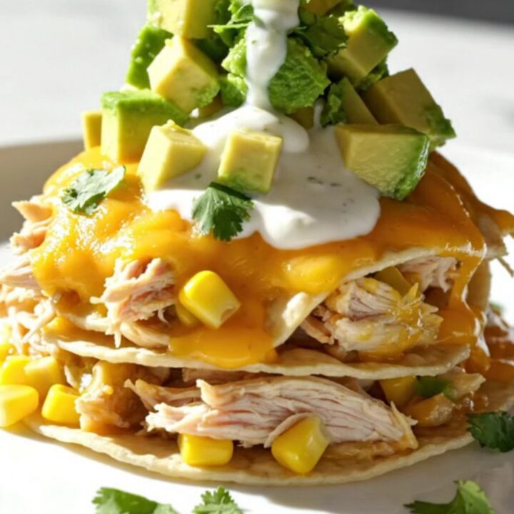 A close-up of the creamy cilantro lime chicken and white corn enchilada bake in a white ceramic slow cooker.