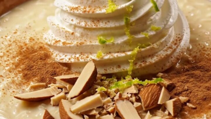 A close-up of creamy Tres Leches Horchata Rice Pudding in a stoneware bowl topped with dulce crema and almonds.