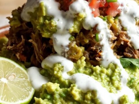 A steaming, cheesy beef barbacoa burrito casserole in a stainless steel slow cooker.