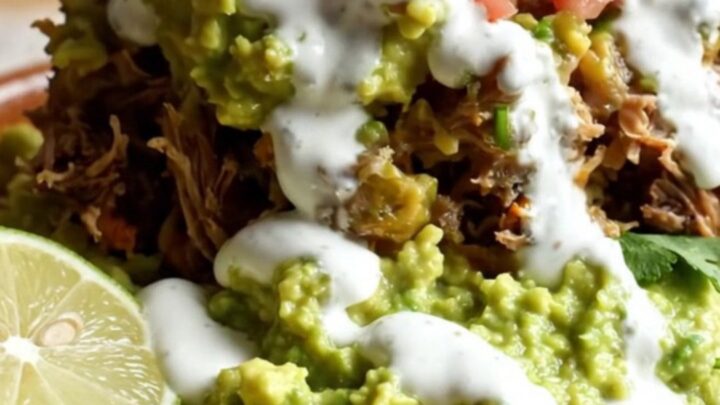 A steaming, cheesy beef barbacoa burrito casserole in a stainless steel slow cooker.