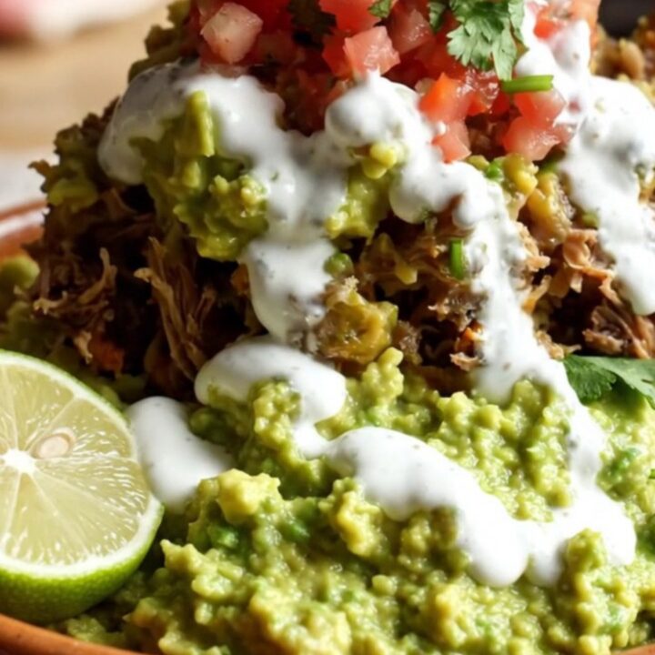 A steaming, cheesy beef barbacoa burrito casserole in a stainless steel slow cooker.