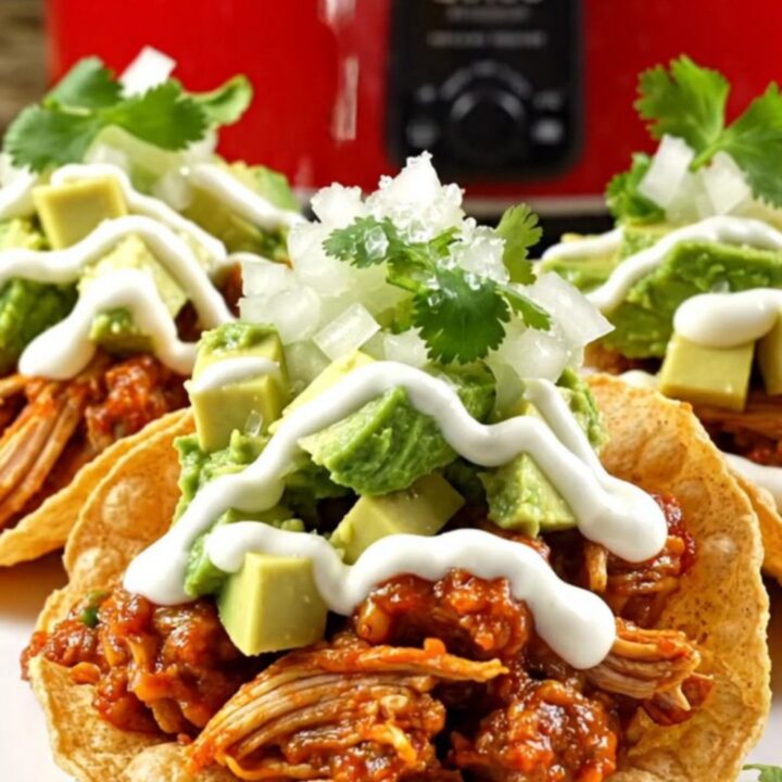 A vibrant plate of crispy chicken queso birria tostadas topped with fresh avocado and cilantro.