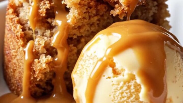 A warm, golden caramel apple dump cake in a glossy cinnamon-red Crockpot, scooped into a white ceramic dish.