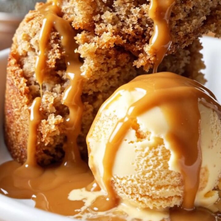 A warm, golden caramel apple dump cake in a glossy cinnamon-red Crockpot, scooped into a white ceramic dish.
