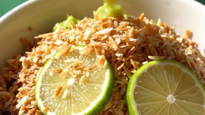 A close-up of a bubbling key lime dump cake in a seafoam green Crockpot with golden crust and lime zest.