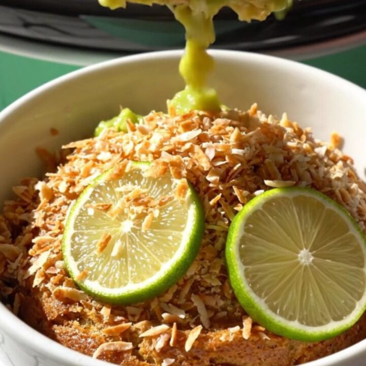 A close-up of a bubbling key lime dump cake in a seafoam green Crockpot with golden crust and lime zest.