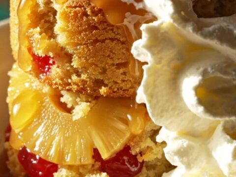 A warm pineapple upside-down cake served in a dessert bowl, topped with whipped cream.