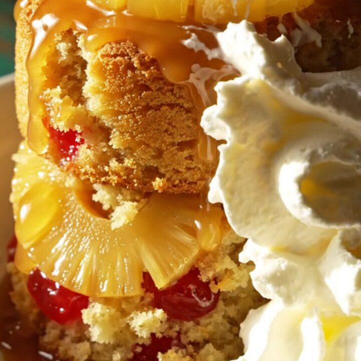 A warm pineapple upside-down cake served in a dessert bowl, topped with whipped cream.
