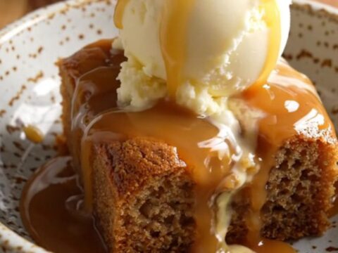 A warm bowl of banana caramel walnut dump cake topped with a melting scoop of vanilla ice cream.