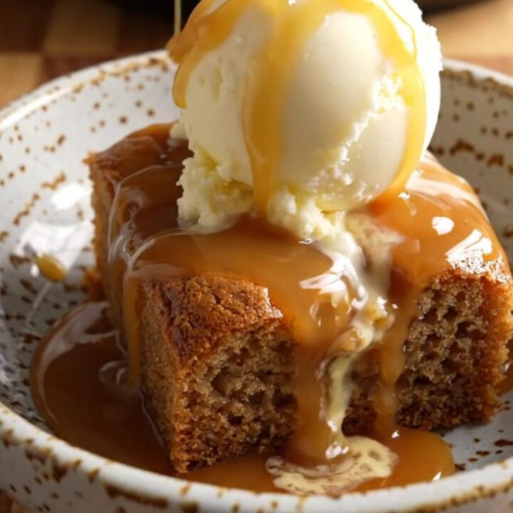 A warm bowl of banana caramel walnut dump cake topped with a melting scoop of vanilla ice cream.