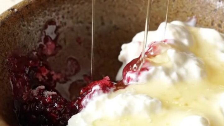 A rustic Crockpot filled with bubbling mixed berry oatmeal dump cake topped with a crispy, golden crust.