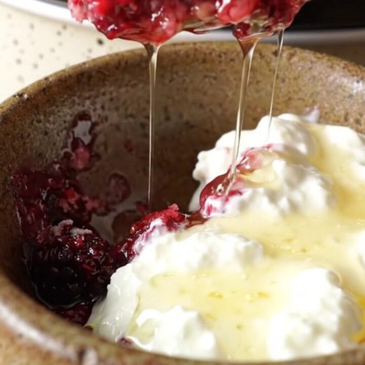 A rustic Crockpot filled with bubbling mixed berry oatmeal dump cake topped with a crispy, golden crust.