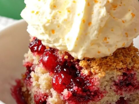 A festive crockpot cranberry orange white chocolate dump cake served in a bowl with whipped mascarpone.