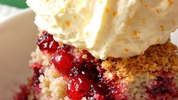 A festive crockpot cranberry orange white chocolate dump cake served in a bowl with whipped mascarpone.