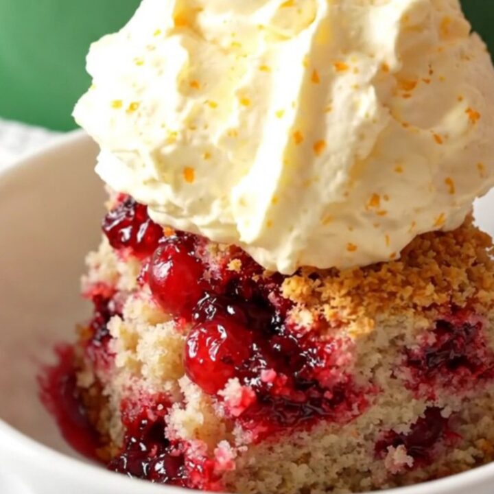 A festive crockpot cranberry orange white chocolate dump cake served in a bowl with whipped mascarpone.