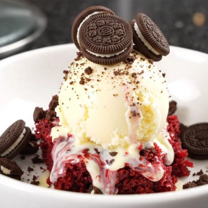 A crimson red velvet Oreo dump cake in a red Crockpot, with cream cheese and chocolate ribbons visible.