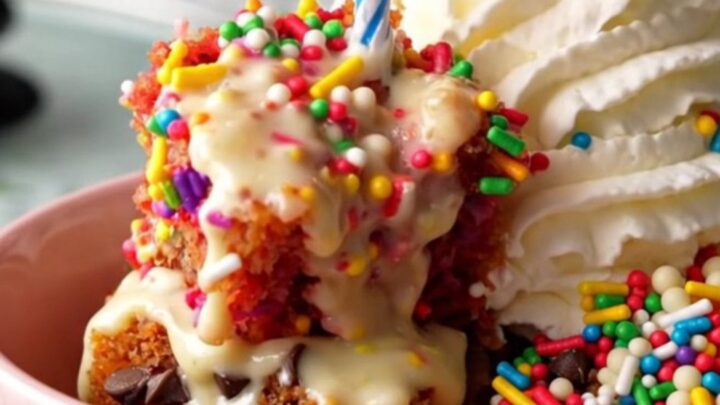 A warm, gooey Funfetti dump cake inside a ceramic slow cooker with rainbow sprinkles.