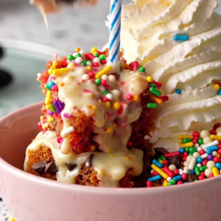 A warm, gooey Funfetti dump cake inside a ceramic slow cooker with rainbow sprinkles.