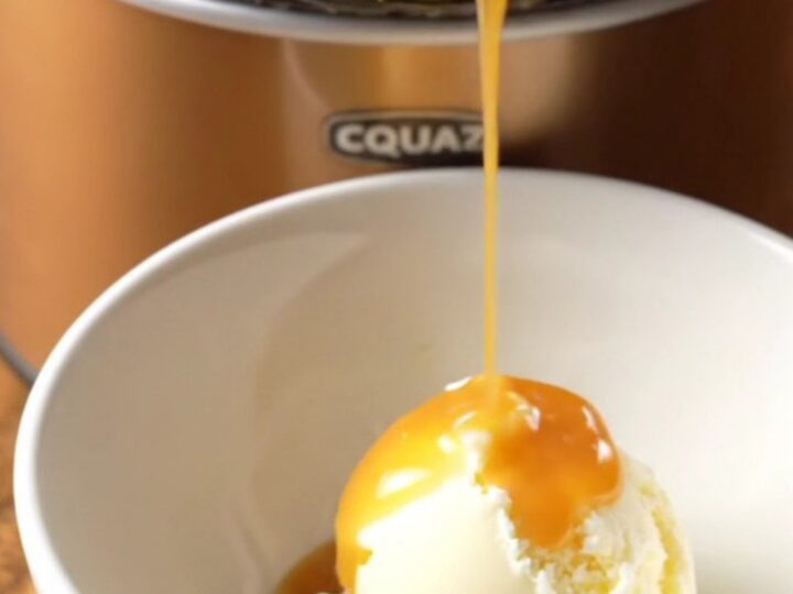 A close-up of a warm butterscotch pecan pudding cake in a crockpot with a spoon scooping out a piece.