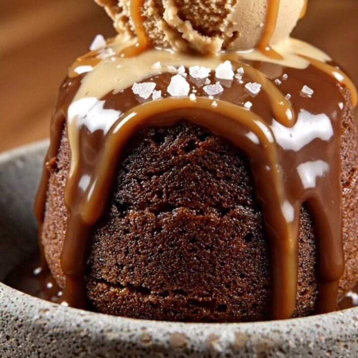 A steaming scoop of chocolate mocha lava cake in a stoneware bowl topped with coffee ice cream and sea salt.