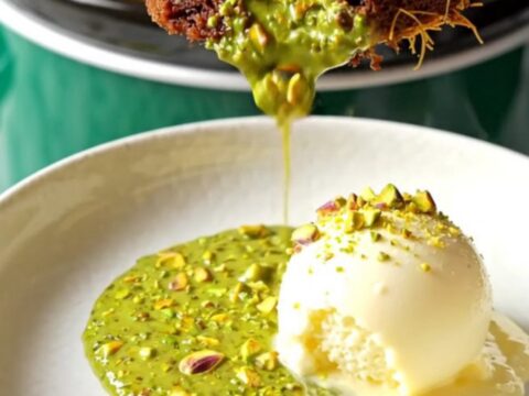 A close-up of a dark chocolate cake in a slow cooker with a molten green pistachio and kataifi center.