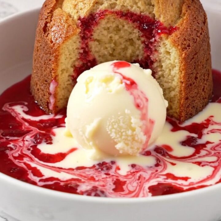 A close-up of a white chocolate raspberry lava cake being scooped from a ceramic slow cooker.