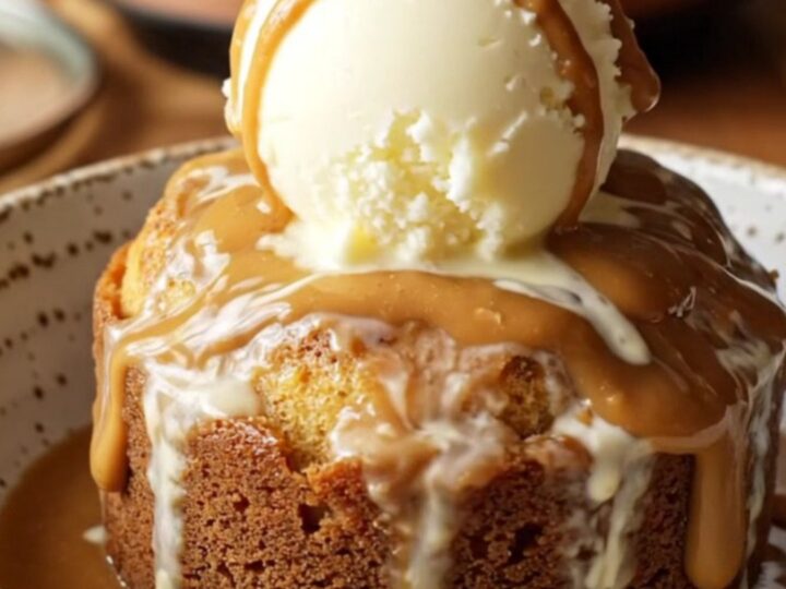 A steaming, golden Biscoff lava cake in a slow cooker, topped with ice cream and a whole cookie.