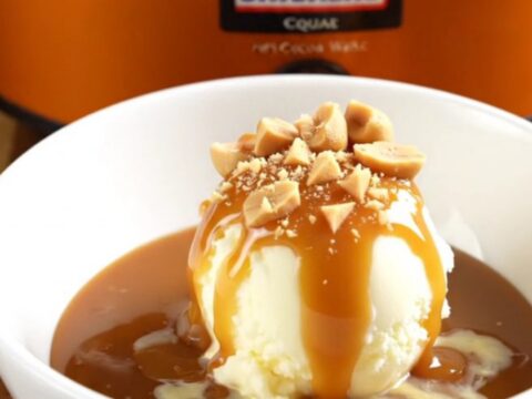 A warm Snickers lava cake in a slow cooker with a spoon scooping out a gooey, caramel-filled portion.
