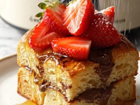 A close-up of a warm Nutella stuffed brioche French toast bake in a ceramic slow cooker.