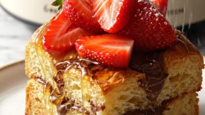 A close-up of a warm Nutella stuffed brioche French toast bake in a ceramic slow cooker.