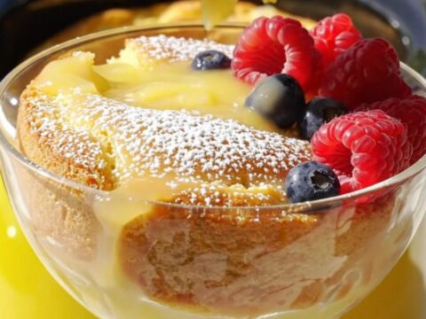 A warm, golden lemon butter cake in a yellow slow cooker with a pool of lemon curd sauce.