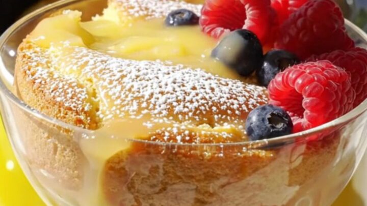 A warm, golden lemon butter cake in a yellow slow cooker with a pool of lemon curd sauce.