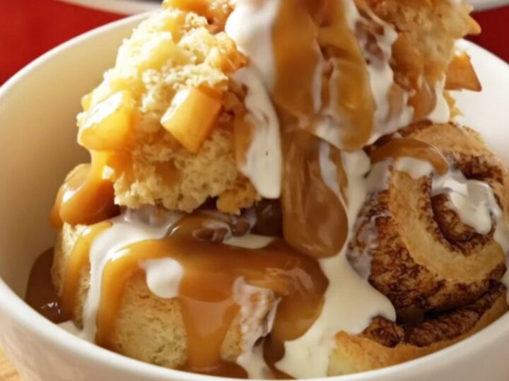 A steaming Crockpot filled with golden, fluffy cinnamon rolls topped with spiced apples and caramel.