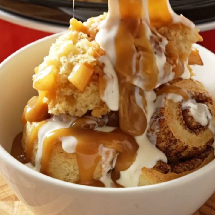 A steaming Crockpot filled with golden, fluffy cinnamon rolls topped with spiced apples and caramel.