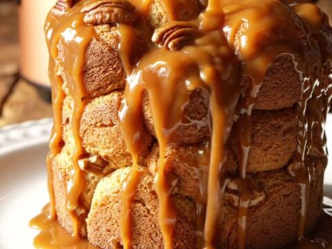 A close-up of pull-apart monkey bread with glossy caramel and toasted pecans in a rustic slow cooker.