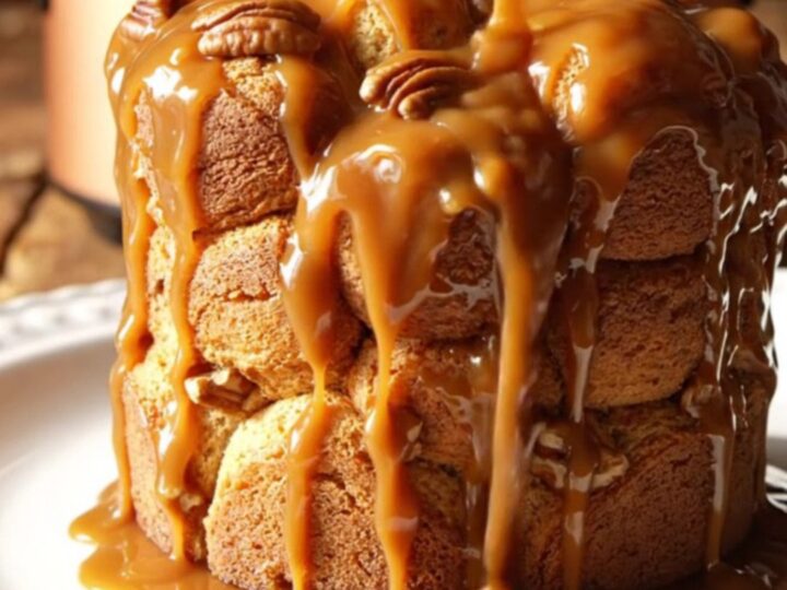 A close-up of pull-apart monkey bread with glossy caramel and toasted pecans in a rustic slow cooker.