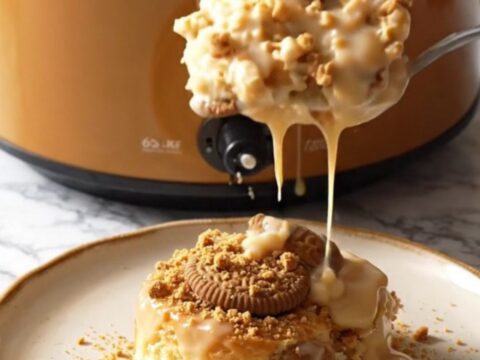 A close-up view of the Biscoff cinnamon roll casserole in a ceramic slow cooker with steam rising.