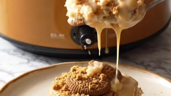 A close-up view of the Biscoff cinnamon roll casserole in a ceramic slow cooker with steam rising.