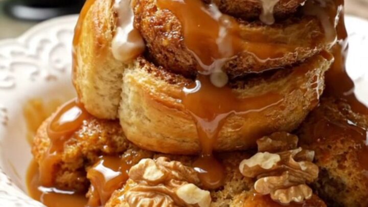 A steaming scoop of Bananas Foster cinnamon roll casserole topped with vanilla ice cream in a white bowl.