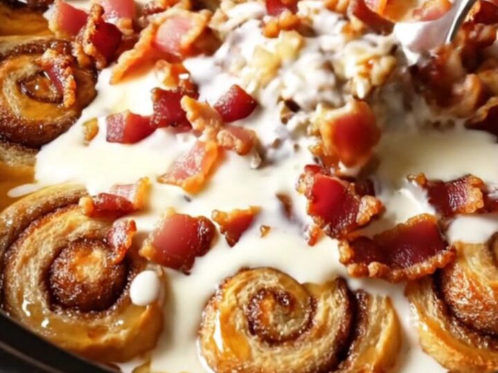 A close-up of a slow-cooker maple bacon cinnamon roll casserole with glistening glaze.