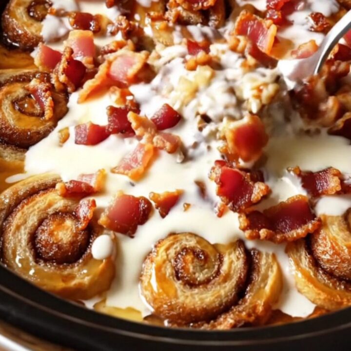 A close-up of a slow-cooker maple bacon cinnamon roll casserole with glistening glaze.