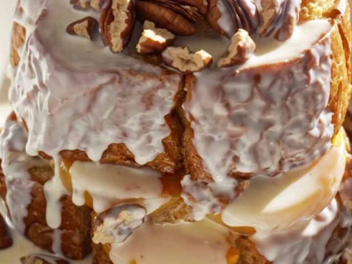 A golden, caramelized peach bourbon brioche French toast bake served in a shallow bowl with pecans.
