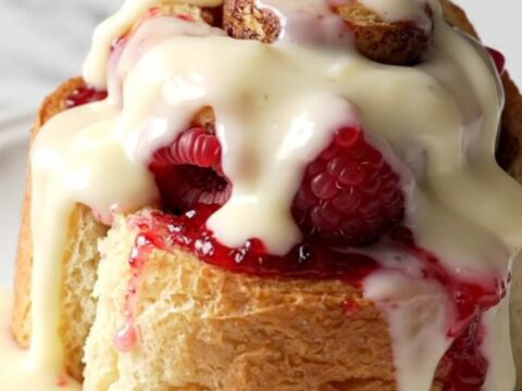 A close-up of a raspberry white chocolate cinnamon roll bake in a pink slow cooker.