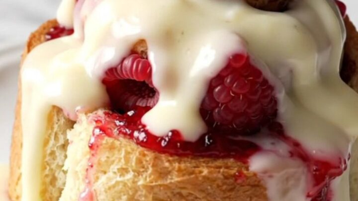 A close-up of a raspberry white chocolate cinnamon roll bake in a pink slow cooker.